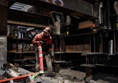 A construction worker crouches beneath steel beams underneath a large government building in Oregon