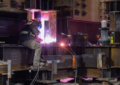 A Pacific Foundation construction worker welds steel shoring towers and micropiles support a building undergoing seismic upgrades.