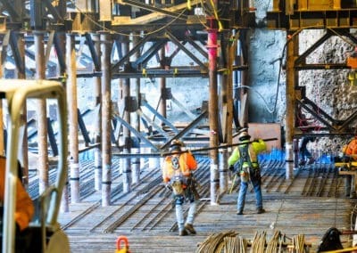 Construction workers carry and set rebar amongst micropiles and steel towers